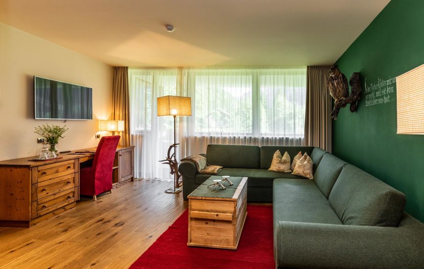 Wohnzimmer mit großer Couch, Schreibtisch und Flatscreen-TV - Romantik Suite Lodge