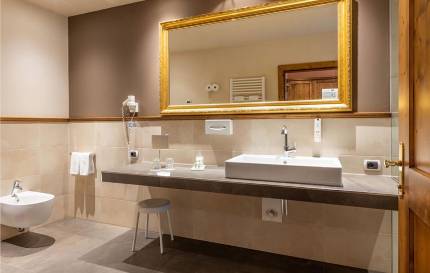 Modern bathroom with bidet, sink and a mirror in a golden frame - Double room Landro Lodge