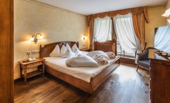 Schlafzimmer der Suite mit Doppelbett, Fernseher und Balkon