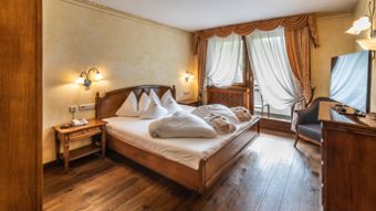 Schlafzimmer der Suite mit Doppelbett, Fernseher und Balkon