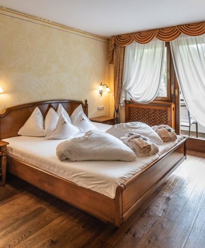 Schlafzimmer der Suite mit Doppelbett, Fernseher und Balkon