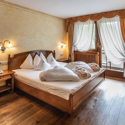 Schlafzimmer der Suite mit Doppelbett, Fernseher und Balkon