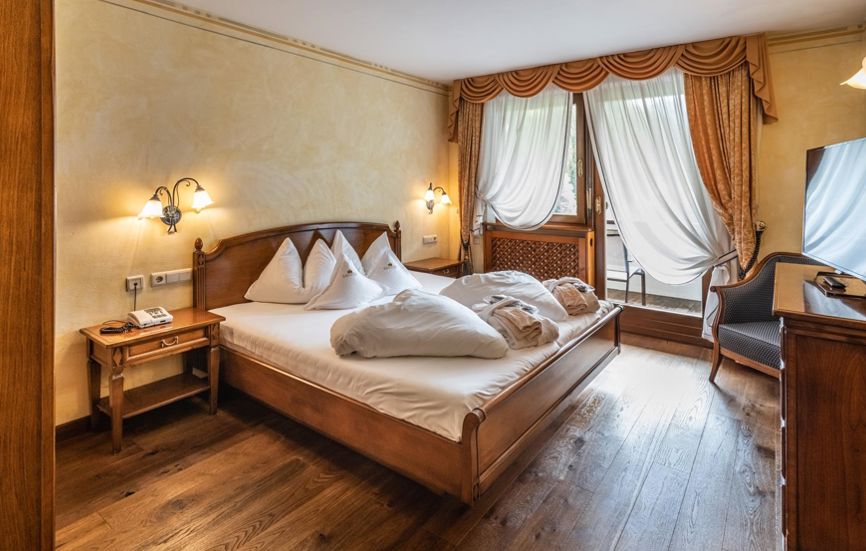 Schlafzimmer der Suite mit Doppelbett, Fernseher und Balkon