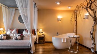 Bedroom with doublebed, bathtub and a tree - Suite Lodge Stephanie