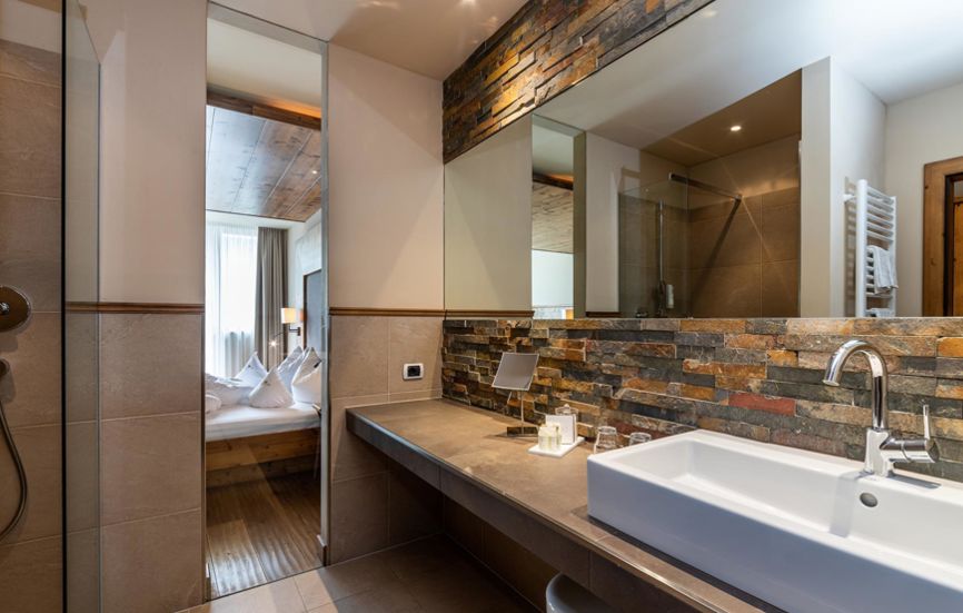 Badezimmer mit natürlichen Materialien, Dusche, Waschbecken und Spiegel - Doppelzimmer Landro Lodge