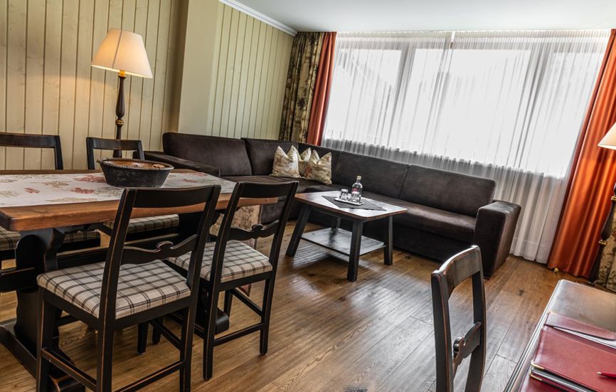 Wohnzimmer mit großer Couch, Schreibtisch und Esstisch für vier Personen - Suite Lodge Norwegian