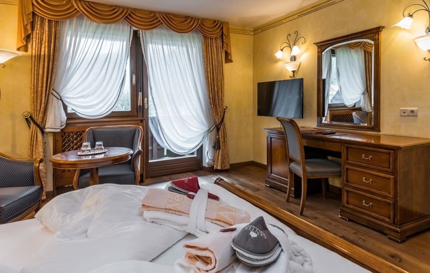 Schlafzimmer der Suite mit Doppelbett, Fernseher und Balkon