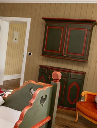 Camera da letto con letto matrimoniale e una poltrona arrancione - Suite Lodge Norwegian