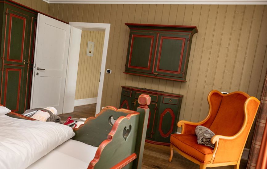 Camera da letto con letto matrimoniale e una poltrona arrancione - Suite Lodge Norwegian